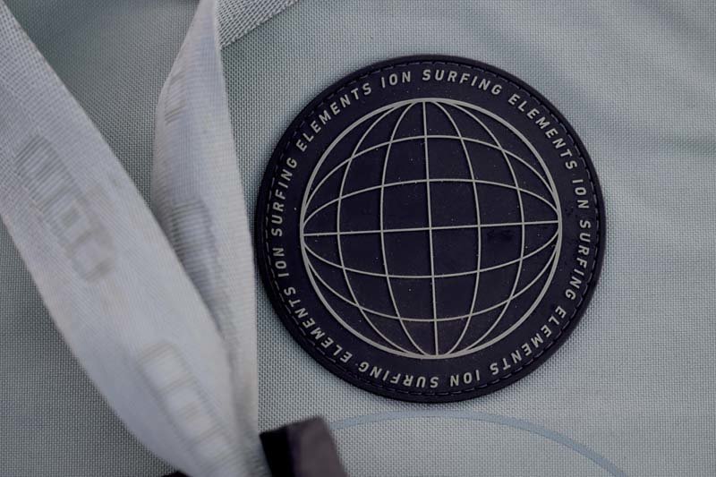 Ion Surfing Elements - Logo mit angedeutetem Erdball auf einer hellen Ion Reisetasche. Schwarzes Logo auf hellem Hintergrund