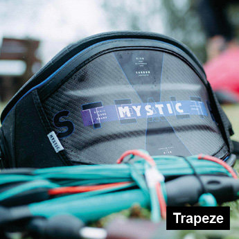 Mystic Stealth Trapez in Schwarz/ Blau liegt im Rasen mit Kite Bar im Vordergrund